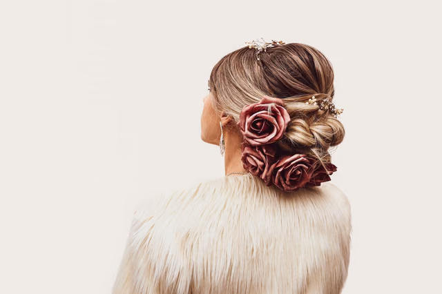 A low bridal bun with burgundy roses, seen from behind
