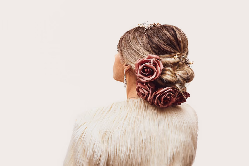A low bridal bun with burgundy roses, seen from behind