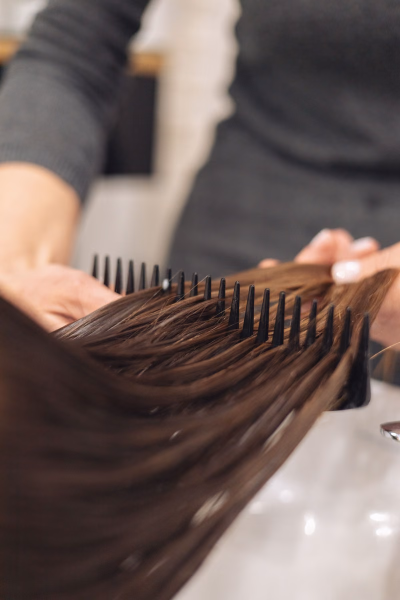 A wide-tooth comb being drawn through smooth hair