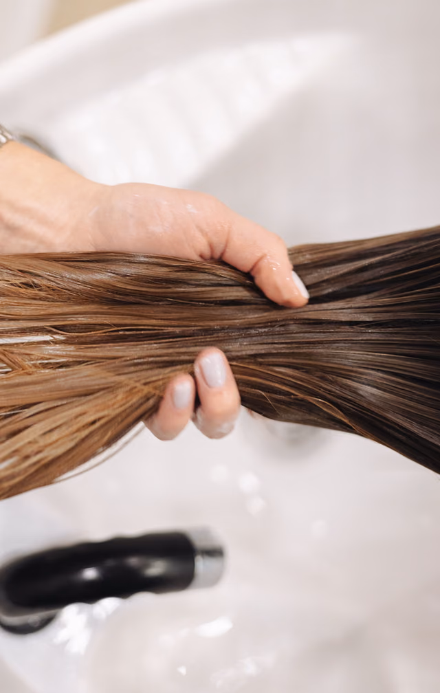 Hands holding a smooth, glossy section of brown hair