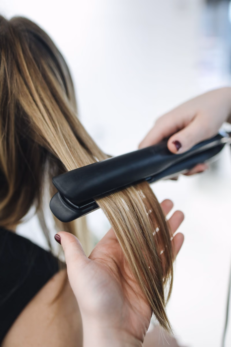 A flat iron gliding through a section of light hair
